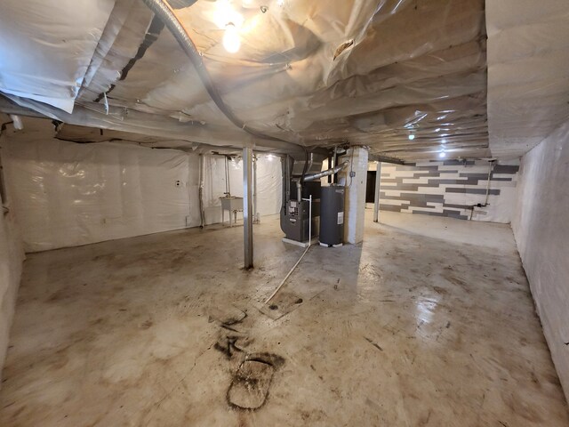 basement featuring water heater, sink, and heating unit