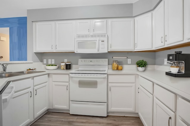 kitchen with white appliances, light hardwood / wood-style flooring, sink, and white cabinets