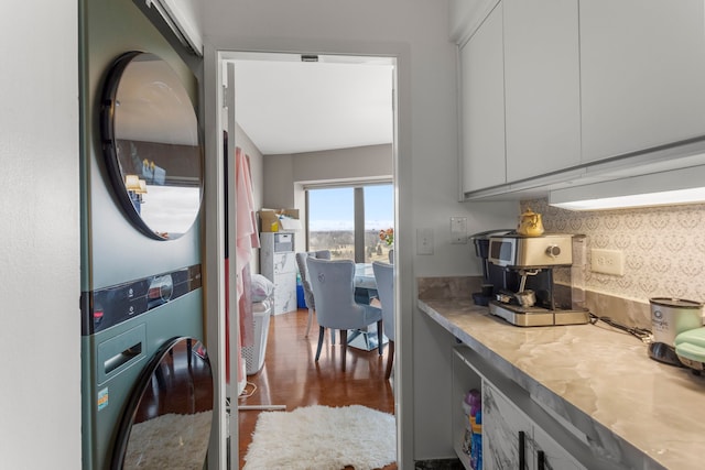 kitchen with white cabinetry, stacked washer and dryer, and dark hardwood / wood-style floors