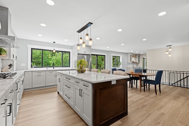 kitchen with stainless steel appliances, a wealth of natural light, pendant lighting, and white cabinets