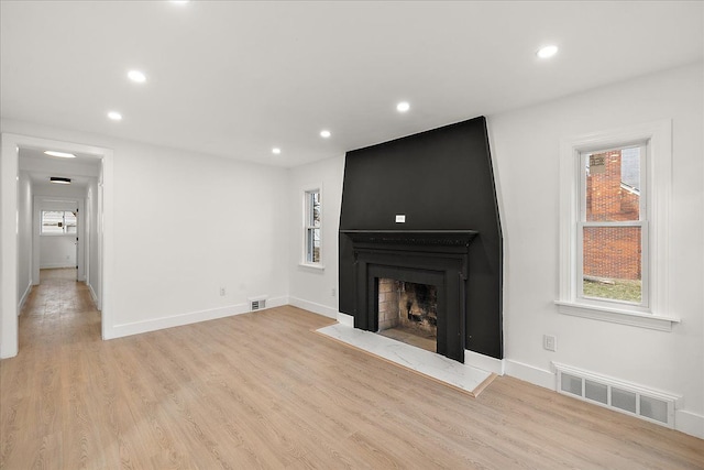 unfurnished living room featuring a large fireplace and light hardwood / wood-style flooring