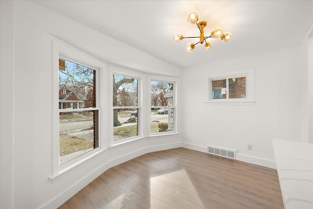 unfurnished dining area featuring an inviting chandelier and wood-type flooring