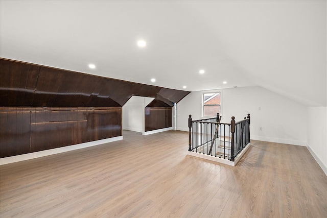 additional living space featuring vaulted ceiling and light hardwood / wood-style floors