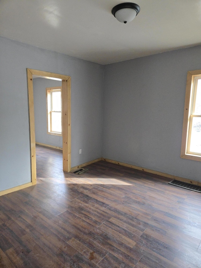 unfurnished room with dark wood-type flooring and baseboards