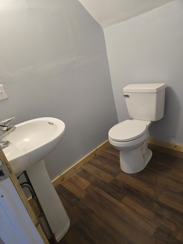 bathroom featuring wood finished floors, toilet, baseboards, and vaulted ceiling