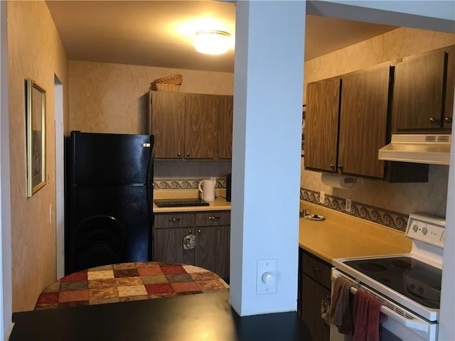 kitchen featuring black fridge, white electric range oven, and tasteful backsplash