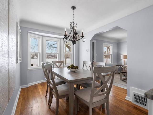 dining area with arched walkways, wood finished floors, visible vents, and baseboards