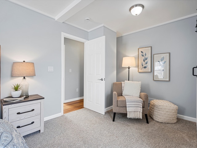 living area featuring beam ceiling, light carpet, and baseboards