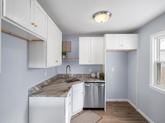 kitchen with baseboards, dishwasher, stone counters, white cabinetry, and a sink