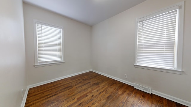 spare room with dark wood-type flooring and a wealth of natural light