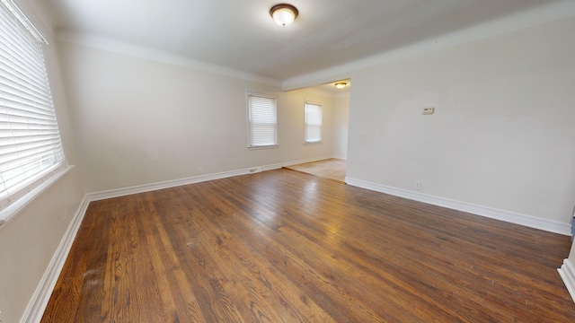 spare room with dark wood-type flooring and a healthy amount of sunlight