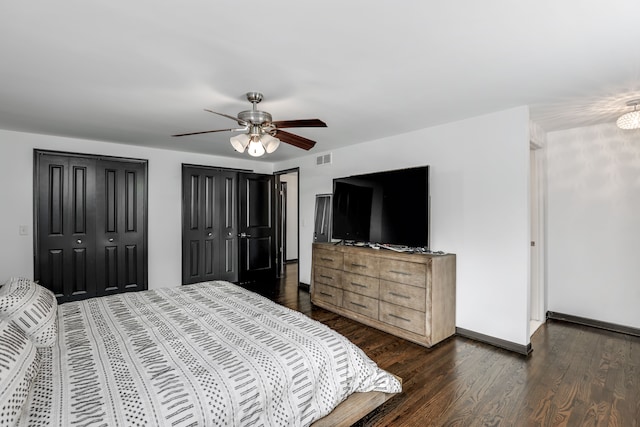 bedroom with dark hardwood / wood-style flooring, multiple closets, and ceiling fan