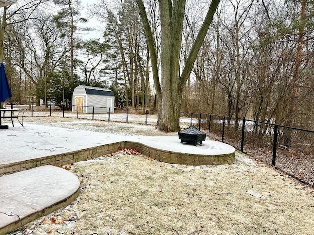 yard covered in snow with an outdoor fire pit and a shed