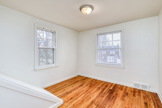 empty room featuring a healthy amount of sunlight and hardwood / wood-style floors