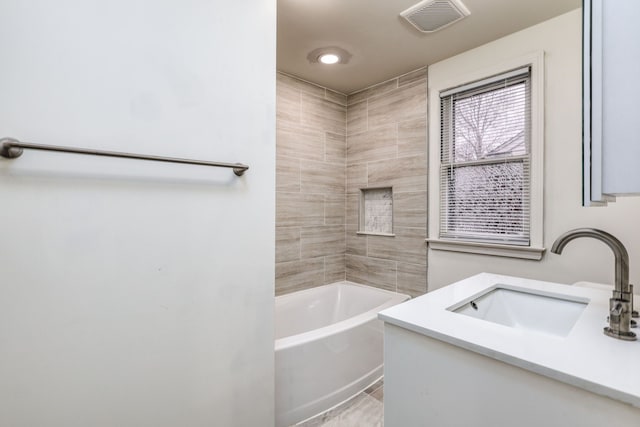 bathroom featuring tiled shower / bath combo and vanity