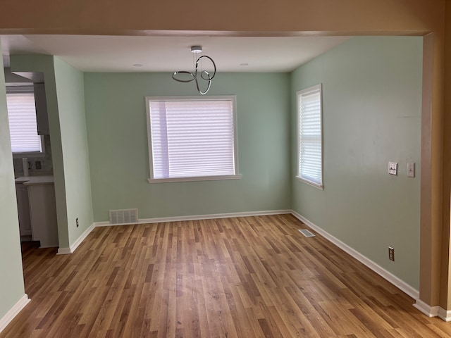 unfurnished dining area with an inviting chandelier and wood-type flooring