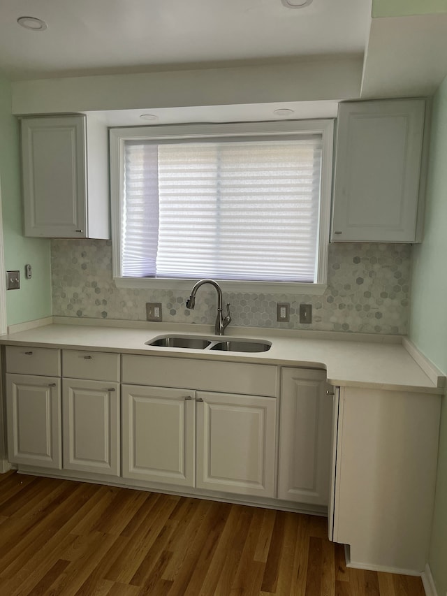 kitchen featuring white cabinetry, sink, hardwood / wood-style floors, and backsplash