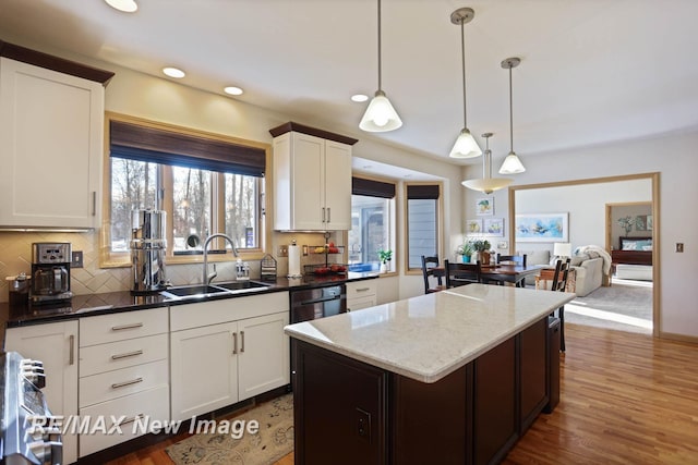 kitchen featuring sink, dark stone countertops, hanging light fixtures, white cabinetry, and tasteful backsplash