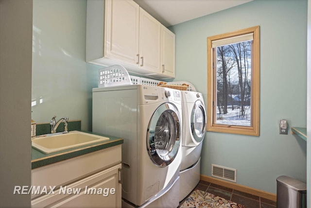 washroom with sink, dark tile patterned floors, cabinets, and washing machine and clothes dryer