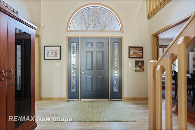 entrance foyer with a towering ceiling and light hardwood / wood-style floors