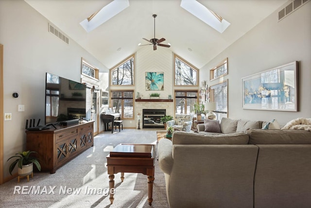 living room with ceiling fan, light carpet, high vaulted ceiling, and a skylight