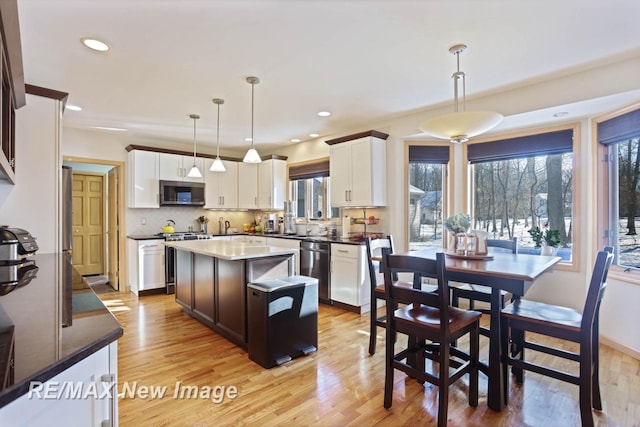 kitchen featuring hanging light fixtures, a kitchen island, light hardwood / wood-style floors, and appliances with stainless steel finishes