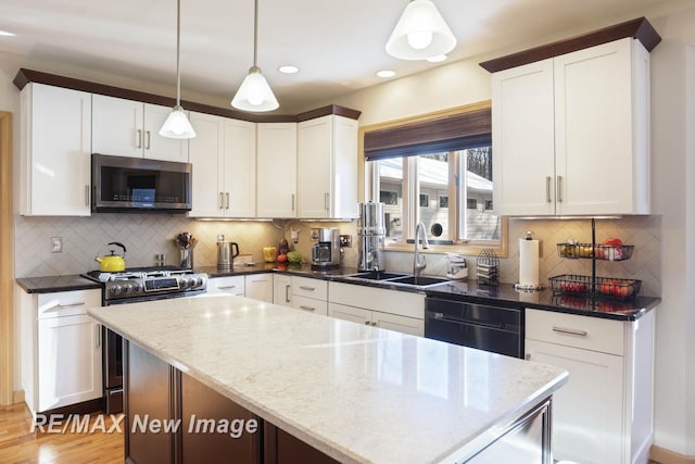 kitchen featuring white cabinetry, dark stone countertops, stainless steel appliances, a kitchen island, and decorative light fixtures