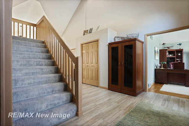 staircase featuring wood-type flooring and high vaulted ceiling