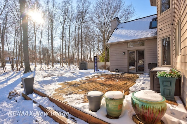 yard layered in snow with a shed and a wooden deck