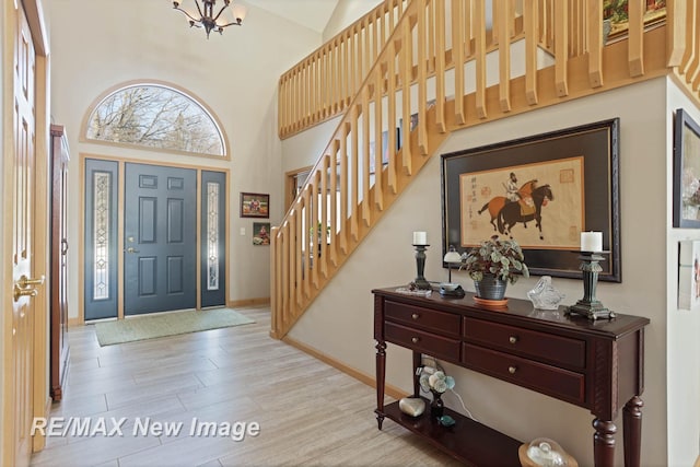 foyer entrance with an inviting chandelier, a high ceiling, and light wood-type flooring