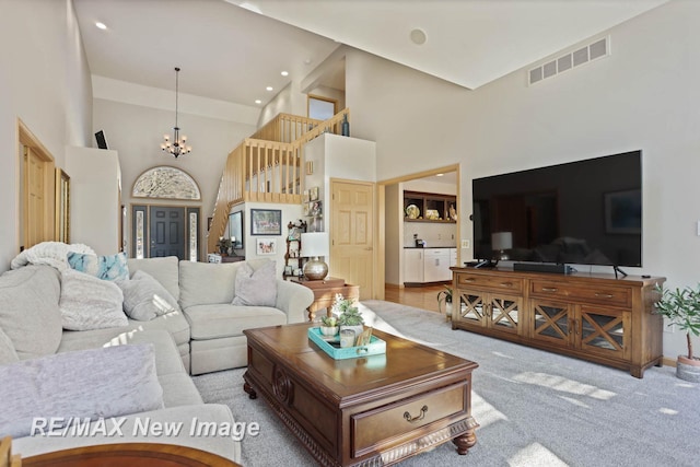 carpeted living room featuring a notable chandelier and a towering ceiling