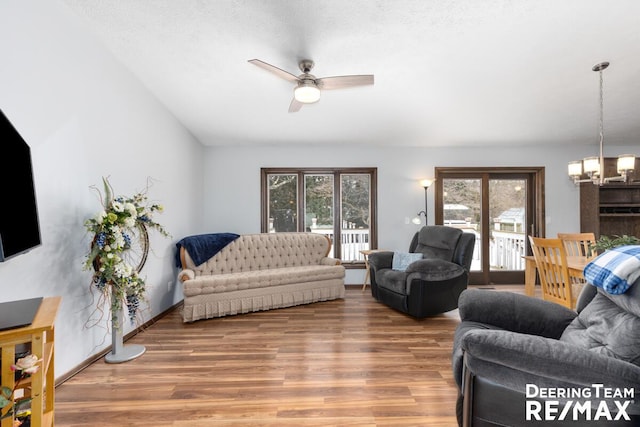 living room with hardwood / wood-style flooring, a healthy amount of sunlight, and ceiling fan with notable chandelier