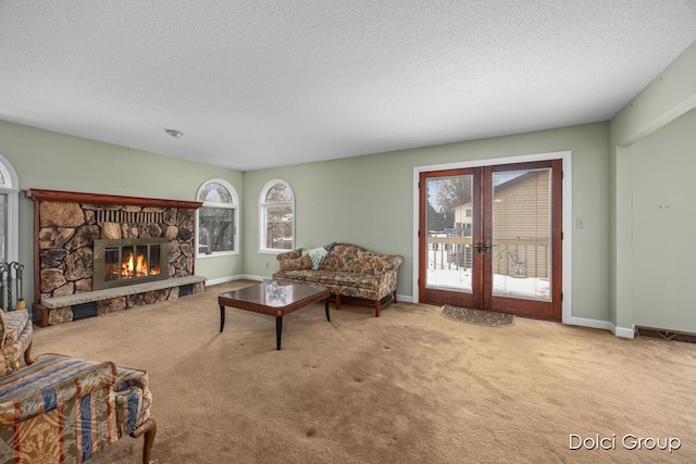 living room with carpet floors, a textured ceiling, a fireplace, and french doors