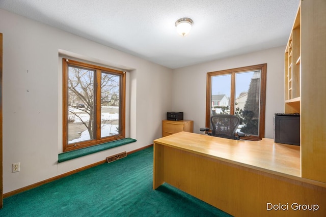 unfurnished office with a textured ceiling and dark colored carpet