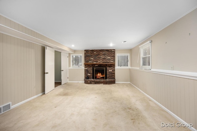 unfurnished living room with crown molding, light colored carpet, and a brick fireplace