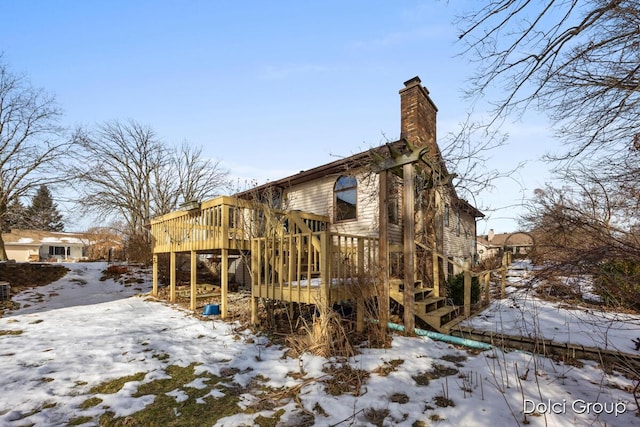 snow covered house featuring a wooden deck