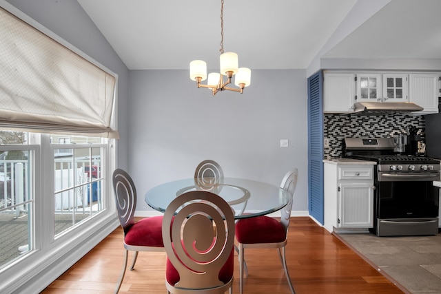 dining area featuring lofted ceiling, hardwood / wood-style floors, and an inviting chandelier