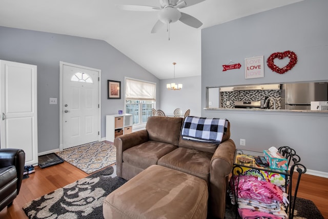 living room with wood-type flooring, lofted ceiling, sink, and ceiling fan with notable chandelier