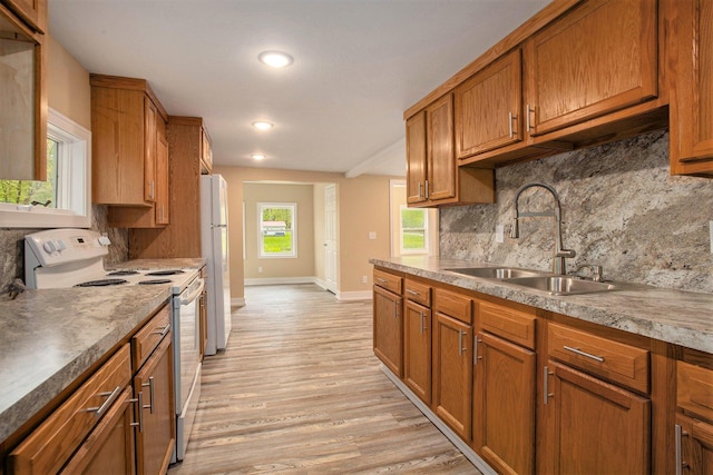 kitchen with sink, decorative backsplash, white appliances, and light hardwood / wood-style floors