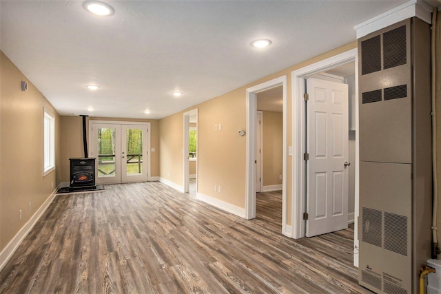 unfurnished living room featuring hardwood / wood-style flooring, french doors, and a wood stove