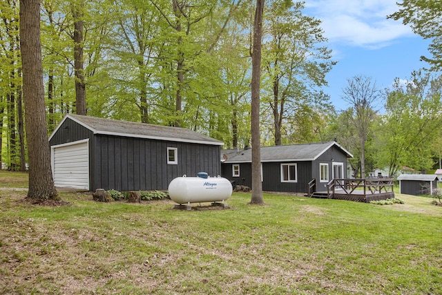 view of yard with a wooden deck, a garage, and an outbuilding