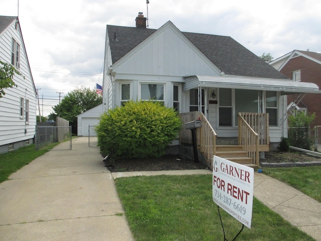 bungalow featuring a garage, an outdoor structure, a front yard, and covered porch