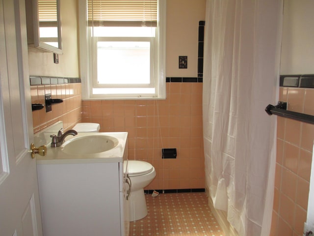 bathroom featuring vanity, a healthy amount of sunlight, tile walls, and toilet