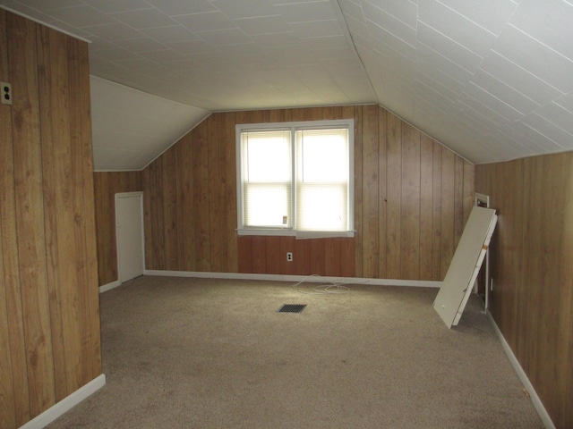 additional living space with lofted ceiling, wooden walls, and light carpet