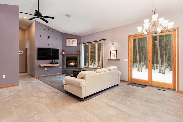 living room featuring ceiling fan with notable chandelier, vaulted ceiling, and a tile fireplace