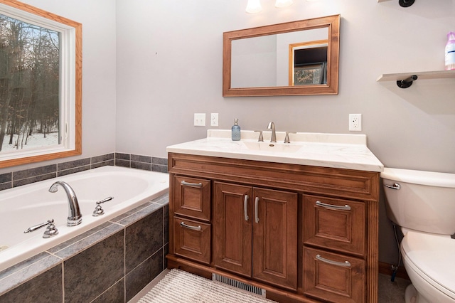 bathroom featuring a relaxing tiled tub, plenty of natural light, and toilet