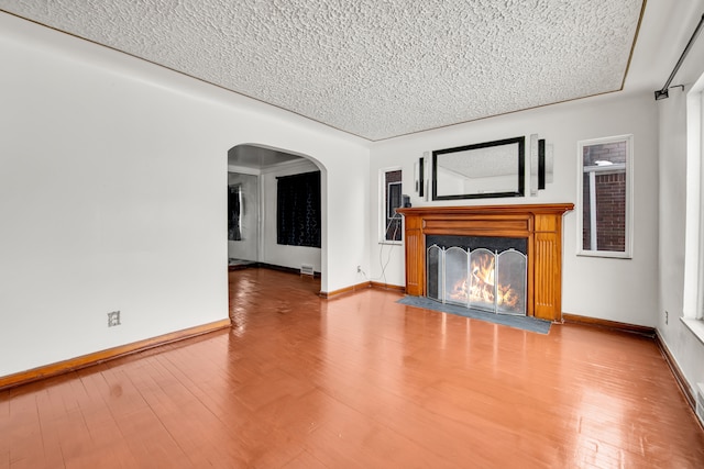 unfurnished living room with wood-type flooring and a textured ceiling