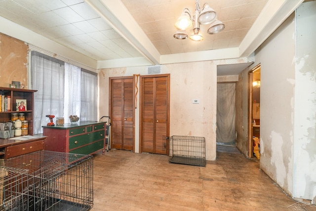 miscellaneous room with hardwood / wood-style flooring, an inviting chandelier, and beam ceiling