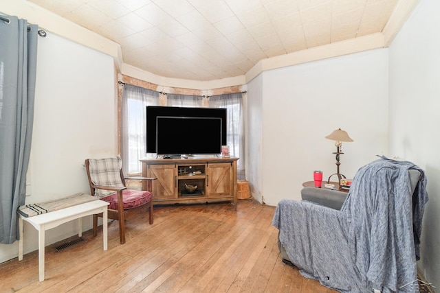 living area with crown molding and light hardwood / wood-style floors