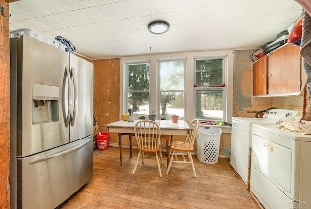 kitchen featuring stainless steel fridge, washer and clothes dryer, and light wood-type flooring